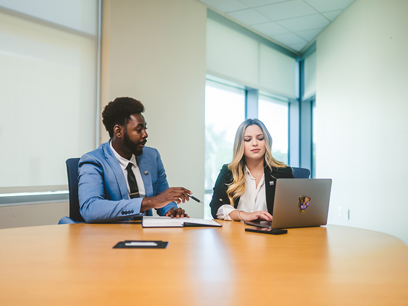Two FIU students in office attire talking